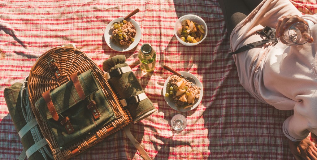 wicker picnic basket and spread on red checkered blanket