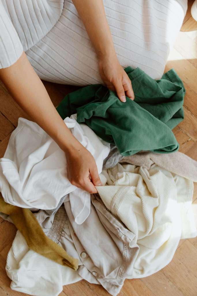 woman sorting through pile of clothes to find something to wear