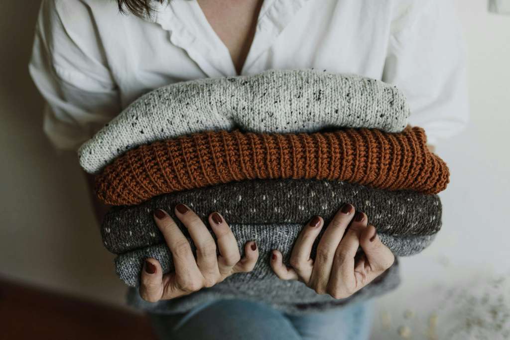 woman holds folded sweaters